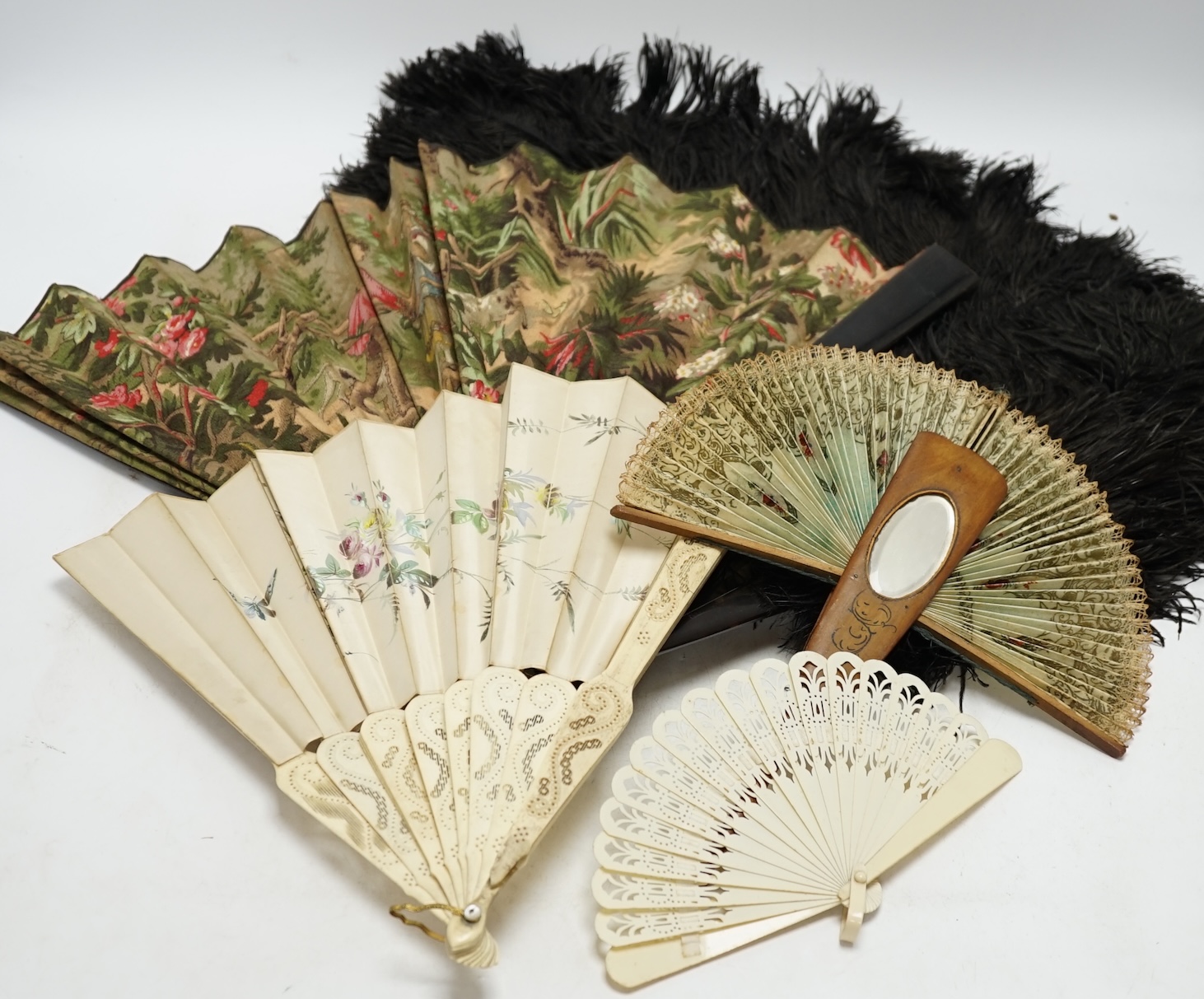 A black ostrich feather and tortoiseshell fan and four others including a carved bone and floral painted silk example. Condition - poor to fair